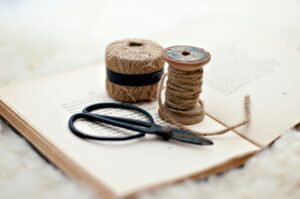Close-up of scissors and twine on a vintage book, ideal for crafting inspiration.